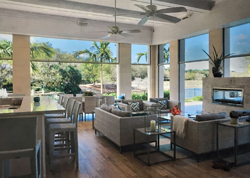 A covered outdoor living room with a bar, lounge seating and a linear fireplace, with motorized screens lowered across the open sides.
